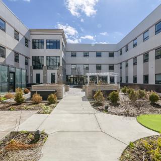 A modern building featuring a landscaped courtyard under a clear sky.