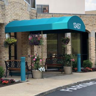 An entrance with a teal awning and potted plants.