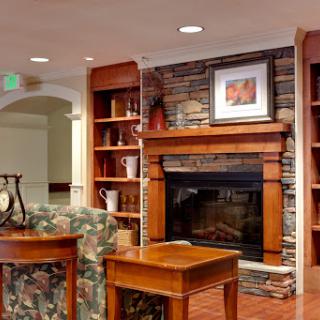 A cozy living room featuring a warm fireplace and wooden shelving, perfect for relaxation.