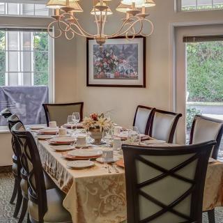 A beautifully set dining table in an elegant dining room with a chandelier.