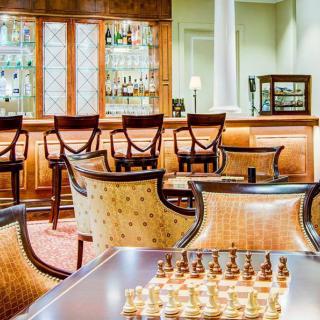 A luxurious bar interior featuring a chessboard and comfortable chairs.
