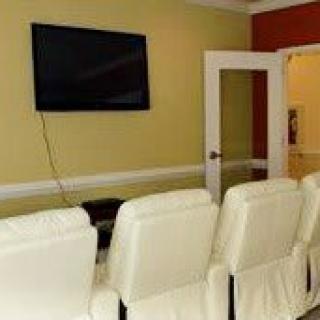 A cozy home theater setup with white seating and a large wall-mounted television.