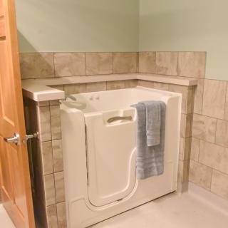 A bathroom featuring a walk-in bathtub with a towel draped over the edge and tiled walls.