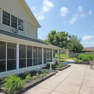 A spacious backyard patio with a screened porch and well-maintained landscaping on a sunny day.