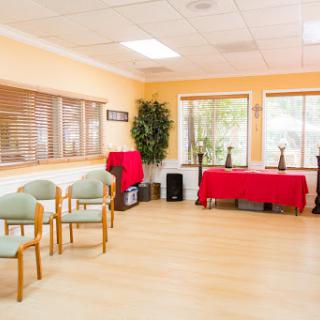 A bright and welcoming waiting area featuring comfortable chairs and a table, adorned with plants and decorative items.