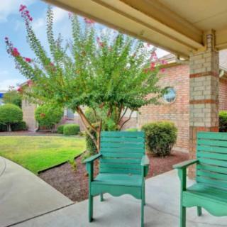 A peaceful patio with green chairs overlooking a garden.