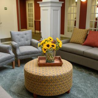 A cozy living room with a sofa, two chairs, and a coffee table adorned with sunflowers.