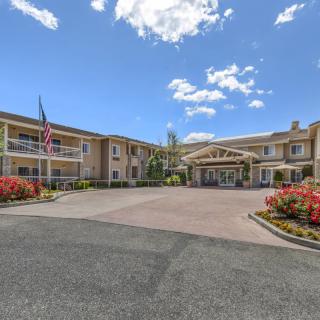 A hotel building with an entrance and well-maintained landscaping under a partly cloudy sky.