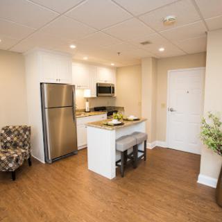 A modern kitchen and living space featuring sleek appliances and cozy seating.