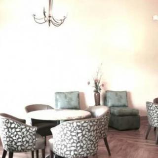 A cozy dining area with patterned chairs and a round table, illuminated by a chandelier.