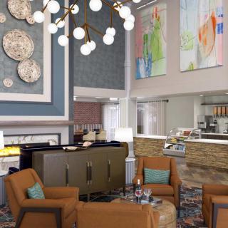 A modern hotel lobby featuring comfortable seating, contemporary artwork, and an elegant chandelier.