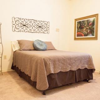 A cozy bedroom with a neatly made bed, decorative wall art, and warm lighting.
