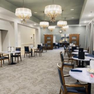 An elegant dining room with chandeliers, tables, and chairs arranged neatly.