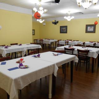 A neatly arranged dining area with tables covered in white tablecloths and chairs around them.