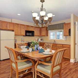 A cozy kitchen and dining area with wooden cabinets, a chandelier, and a neatly set table.