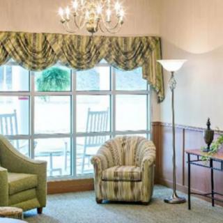 A cozy living room with armchairs, a chandelier, and large windows.