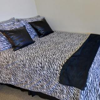 A bed with zebra print bedding and black pillows.