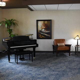 A cozy living space featuring a grand piano, artwork on the wall, and comfortable seating with ambient lighting.