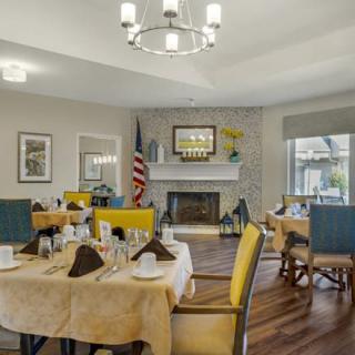 A cozy dining room with neatly set tables and a fireplace, creating an inviting atmosphere.