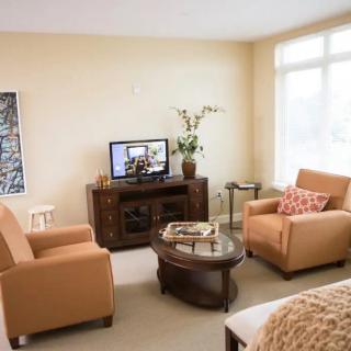 A cozy living room with two armchairs, a wooden coffee table, and a TV stand, creating an inviting and comfortable atmosphere.