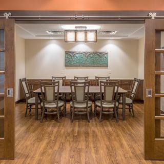 A modern conference room with a large table and chairs, featuring wooden floors and stylish decor.
