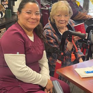 A caregiver smiles alongside an elderly resident, highlighting the bond formed in a supportive environment.