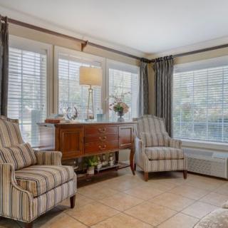 A cozy living room with striped armchairs and large windows.