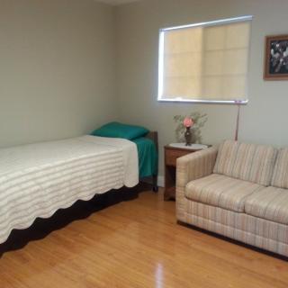 A minimalist bedroom with a single bed and a striped couch.