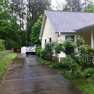 A suburban house with a driveway and garden on a rainy day.