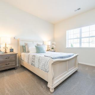A bright and cozy bedroom with a neatly made bed, side tables, and soft lighting.