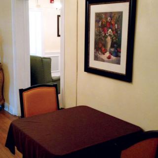 A cozy dining area with a table and chairs, adorned by a framed painting on the wall.