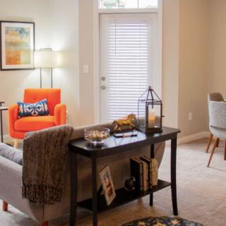 A cozy living room with modern decor, featuring a bright orange chair and elegant furnishings.