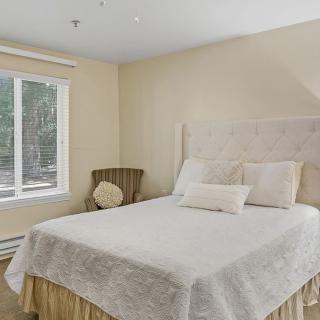 A cozy bedroom with a neatly made bed and a window letting in natural light.