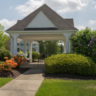 A charming gazebo surrounded by lush landscaping and vibrant flowers on a sunny day.
