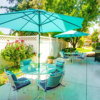 A sunny backyard patio with comfortable outdoor seating and turquoise umbrellas.