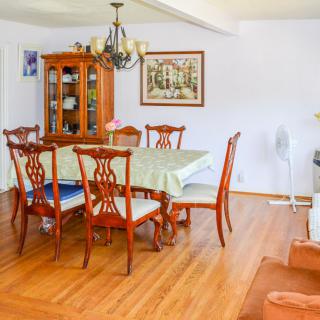 A well-lit dining room with a wooden table and chairs, a glass cabinet, and a chandelier.