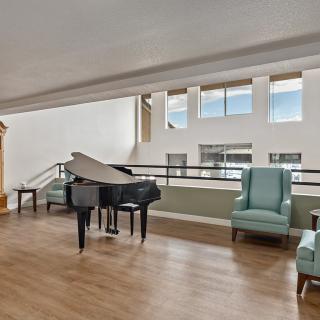 A modern lounge area featuring a grand piano and comfortable seating with ample natural light from large windows.