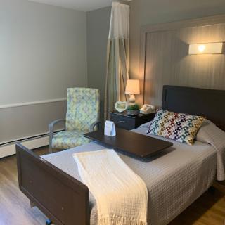 A cozy and inviting bedroom with a neatly made bed, an armchair, and soft lighting.