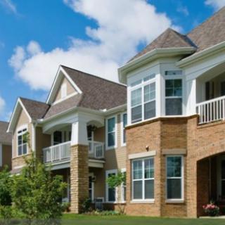 Modern residential townhouses with brick exteriors and balconies under a blue sky.