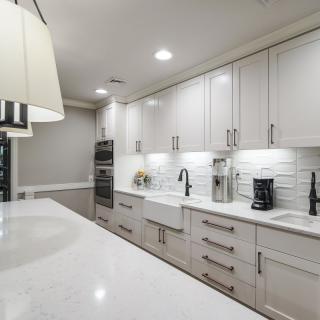 A modern kitchen with white cabinets and a sleek design, featuring a subway tile backsplash and stainless steel appliances.