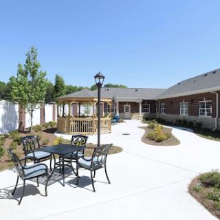 A sunny outdoor courtyard featuring a gazebo and seating area, surrounded by well-maintained landscaping.