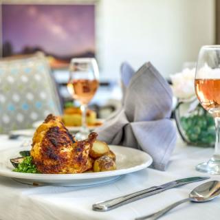 An elegant dining setup featuring a gourmet roast chicken dish served with wine.