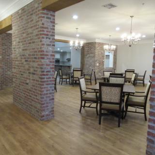 A spacious dining area with brick walls, wooden flooring, and elegant chandeliers.