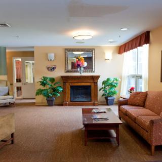 A cozy living room with a sofa, coffee table, and fireplace adorned with decorative plants.