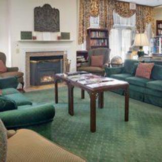 A cozy living room featuring a fireplace, green sofas, and a central table with magazines.