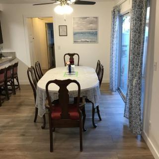 A cozy dining room with a table set for six, featuring elegant chairs, a ceiling fan, and a painting on the wall.