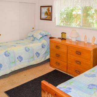 A cozy bedroom with twin beds, a wooden dresser, and a window with curtains.
