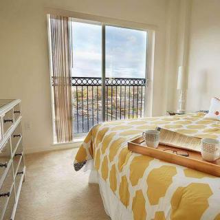 A cozy bedroom with a large window, patterned bedding, and a wooden tray on the bed.