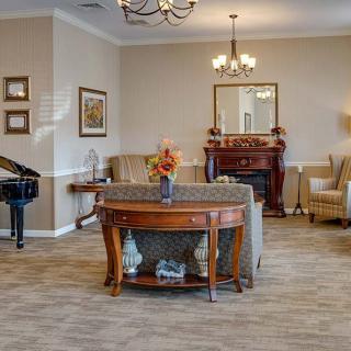 A sophisticated living room with elegant furniture, a piano, and a fireplace.