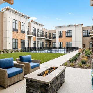 Modern apartment complex courtyard with comfortable outdoor seating and a fire pit.